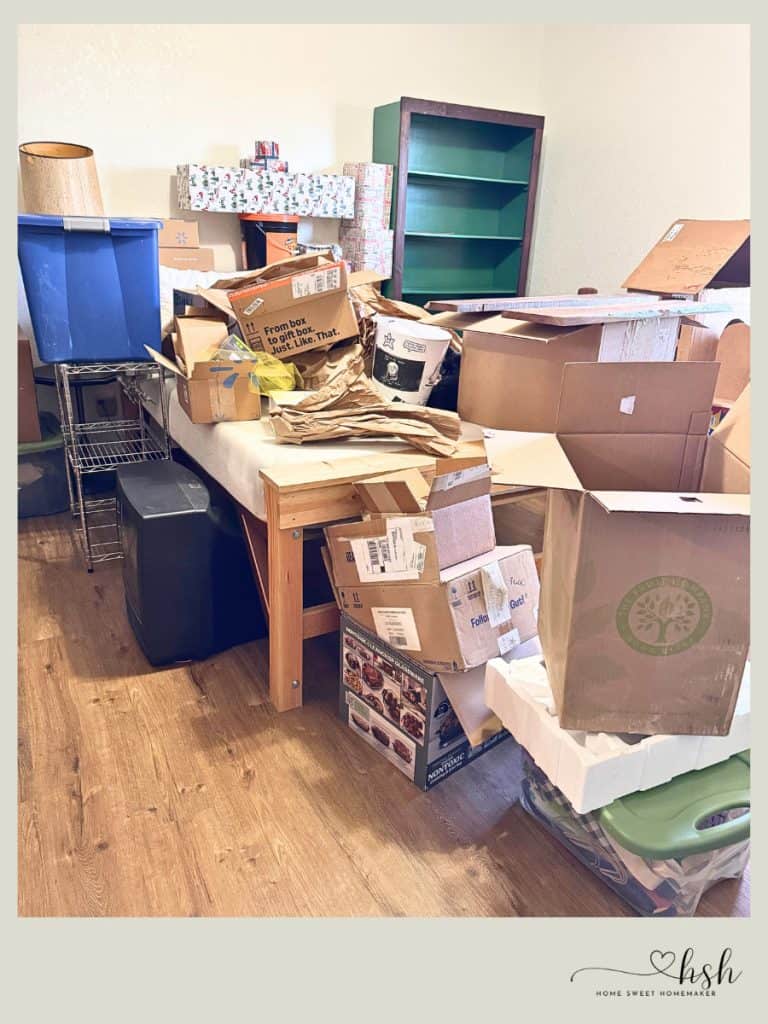 4-Week January Cleaning Schedule With Printable 6 A room cluttered with cardboard boxes and storage bins awaits organization as part of a January cleaning schedule plan.