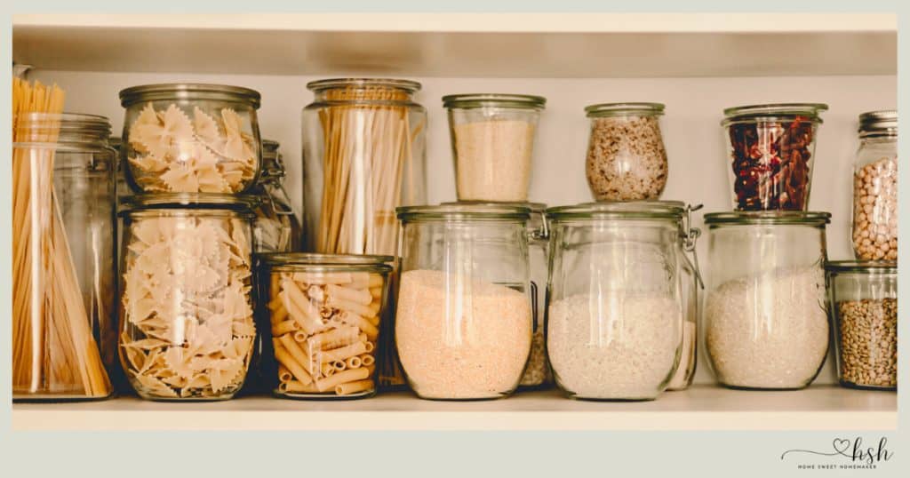 Organized glass jars of pasta and grains in a pantry, essential staples for easy January slow cooker recipes.
