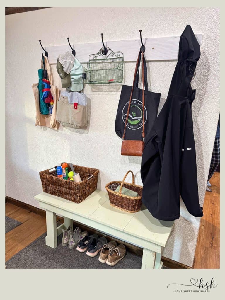 Organized entryway with wall hooks, bench storage, and baskets demonstrating practical home resolutions for new year organization systems.