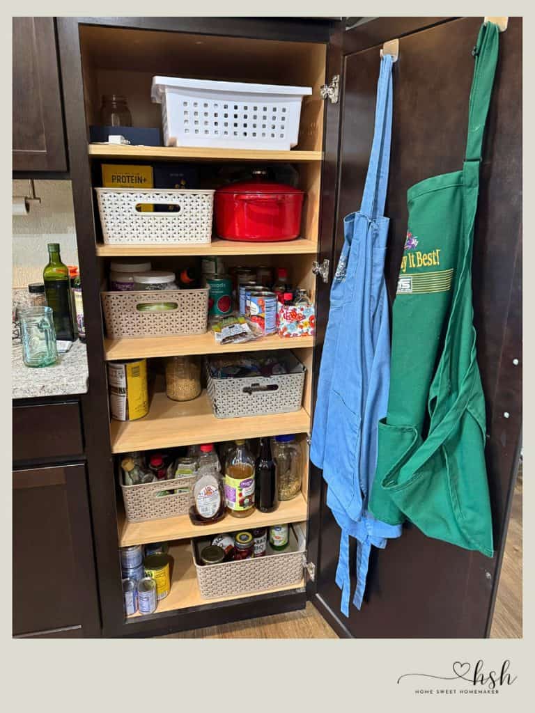 How to Organize a Small Kitchen on a Budget | Complete Guide 2 Tall pantry cabinet with open shelves using white woven baskets to organize cooking ingredients, oils, and dry goods in small kitchen.