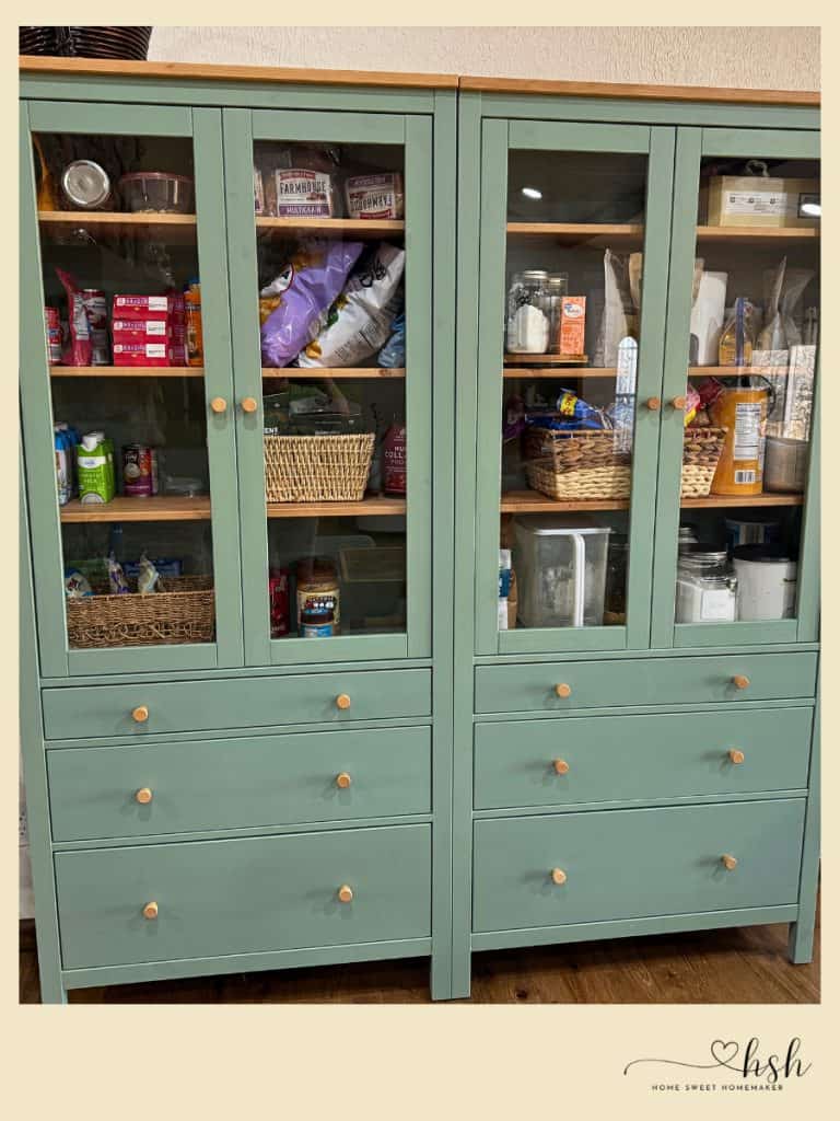 How to Organize a Small Kitchen on a Budget | Complete Guide 7 Two sage green glass-front cabinets with wooden shelves organizing pantry items using wicker baskets for small kitchen storage solution.