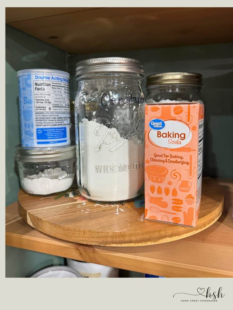 How to Organize a Small Kitchen on a Budget | Complete Guide 10 Mason jars storing baking ingredients with baking soda box on wooden lazy Susan turntable creating accessible small kitchen pantry organization solution.