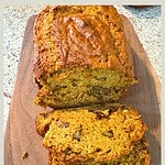 Freshly baked pumpkin banana bread sliced on wooden cutting board showing nutty texture