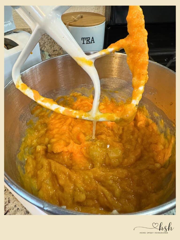 White stand mixer beating wet ingredients for pumpkin banana bread batter until smooth