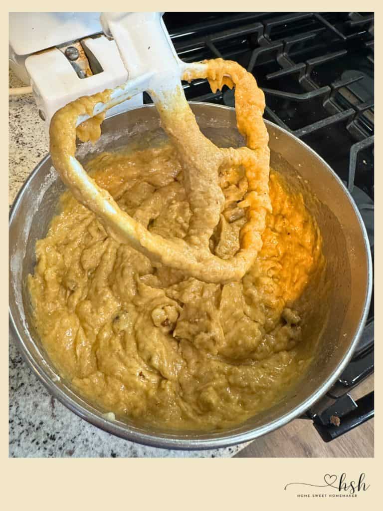 Creamy pumpkin banana bread batter being mixed with electric beaters in stainless steel bowl