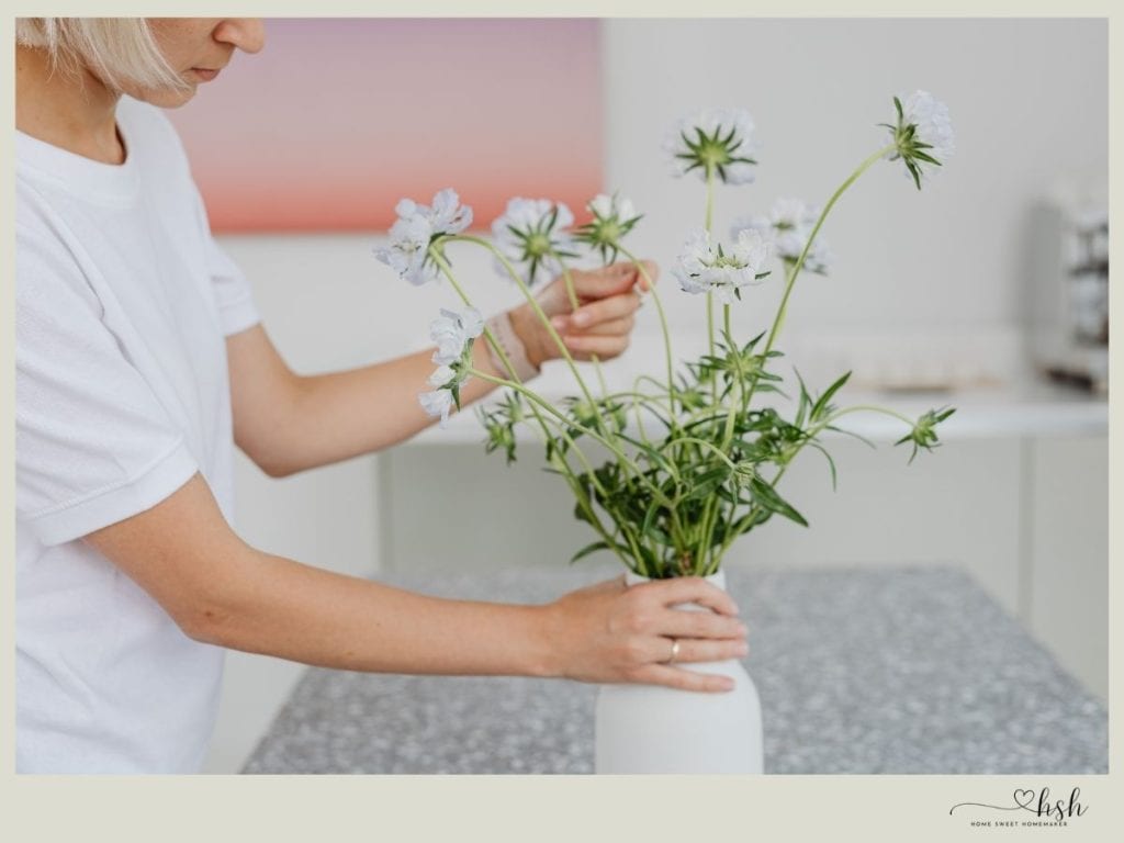 Person arranging flowers in vase.